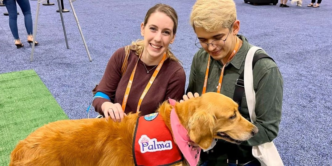 Attendees relaxing with dogs in the Paws for Puppies Lounge at GlassBuild America