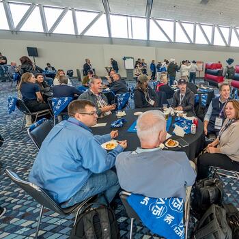 GlassBuild attendees eating and talking during a 2023 party
