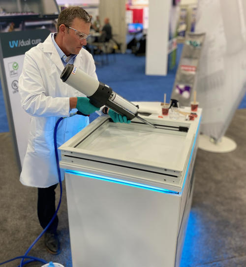 man in lab coat demonstrates use of portable glazing sealant